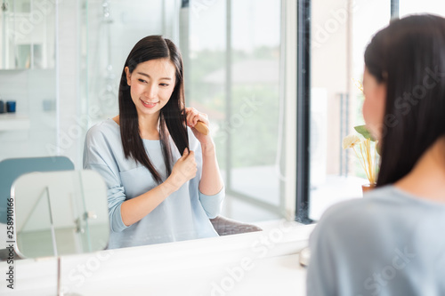 Canvas Print Beauty Asian woman combing hair front of mirror