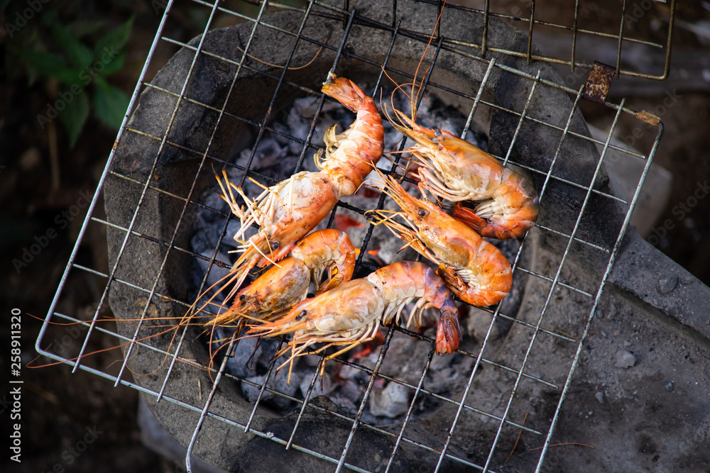 Grilling a prawns BBQ in Thai seafood style.  Traditional grilling by using a black charcoal wood. Top view close up.