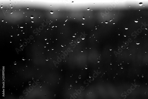 Rain drops on window with blured background in black and white.