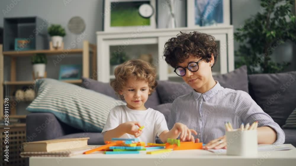 Happy mother and little son are playing with colorful toy bricks at home enjoying construction. Educational games, carefree childhood and apartments concept. Happy mother and little son are playing with colorful toy bricks at home enjoying construction. Educational games, carefree childhood and apartments concept.