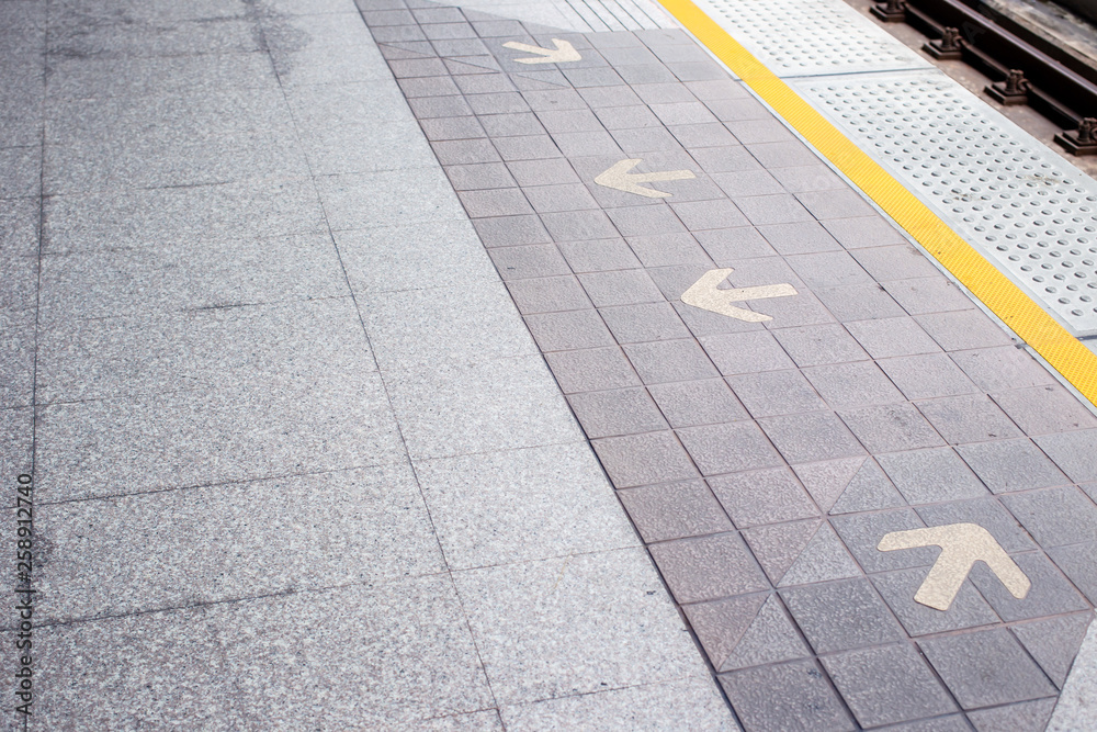 Fototapeta premium Photograph of rail station platform with an entrance and exit arrow sign on the floor.