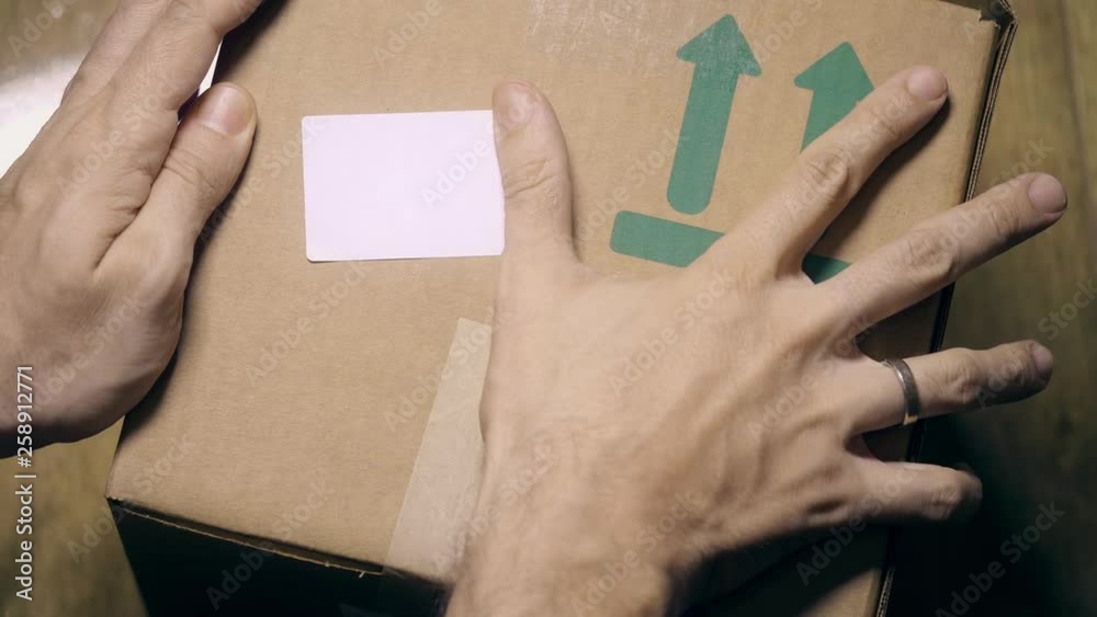 Man sticks a white sticker label to parcel carton box. Place for revealing text or logo