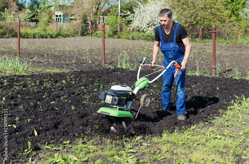 Принти на полотні Man working in the spring garden with tiller machine