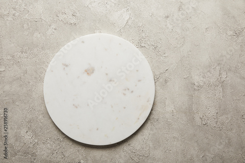 Top view of round marble tray on textured surface