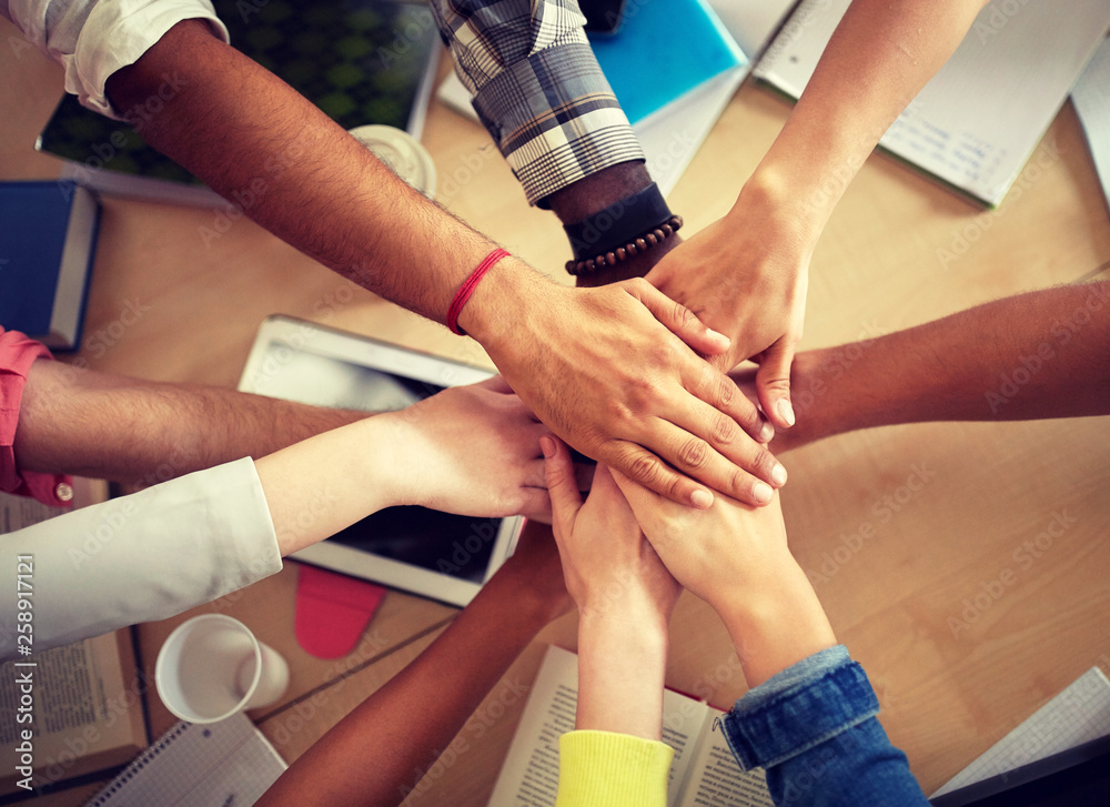 education, school, teamwork and people concept - group of international students with hands on top of each other over table education, school, teamwork and people concept - group of international students with hands on top of each other over table