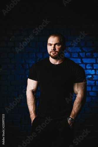 Young handsome sportsman bodybuilder weightlifter with an ideal body, after coaching poses in front of the camera. In sportswear.