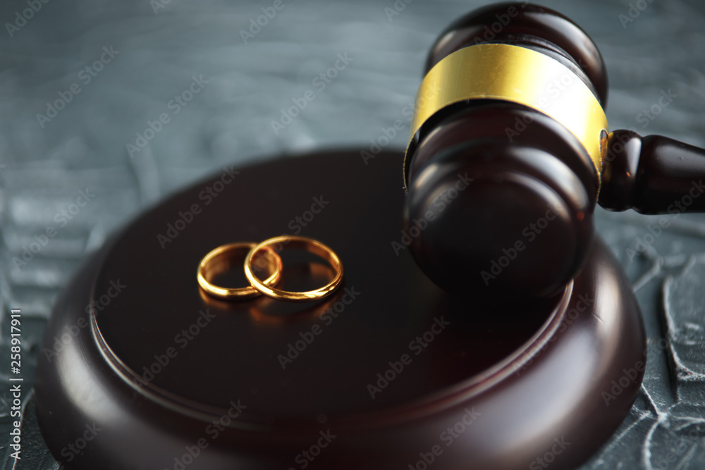 Two broken golden wedding rings divorce decree document.