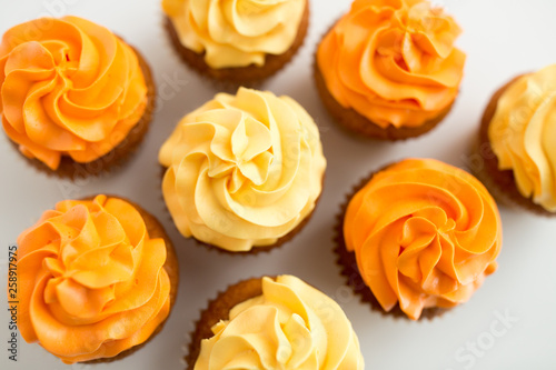food, pastry and confectionery concept - cupcakes with buttercream frosting from top