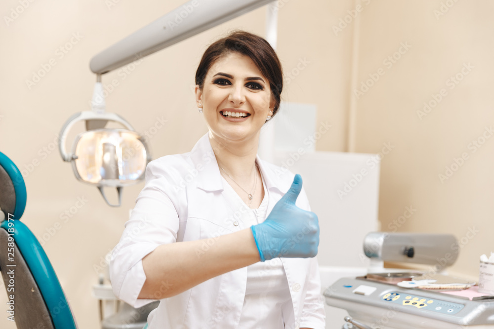 Closeup photo of female dentist in the dental room showing thumb Closeup photo of female dentist in the dental room showing thumb