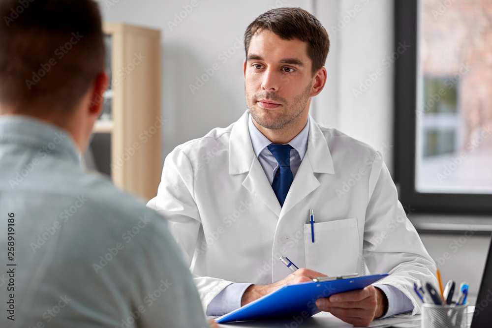 medicine, healthcare and people concept - doctor with clipboard and male patient at medical office in hospital