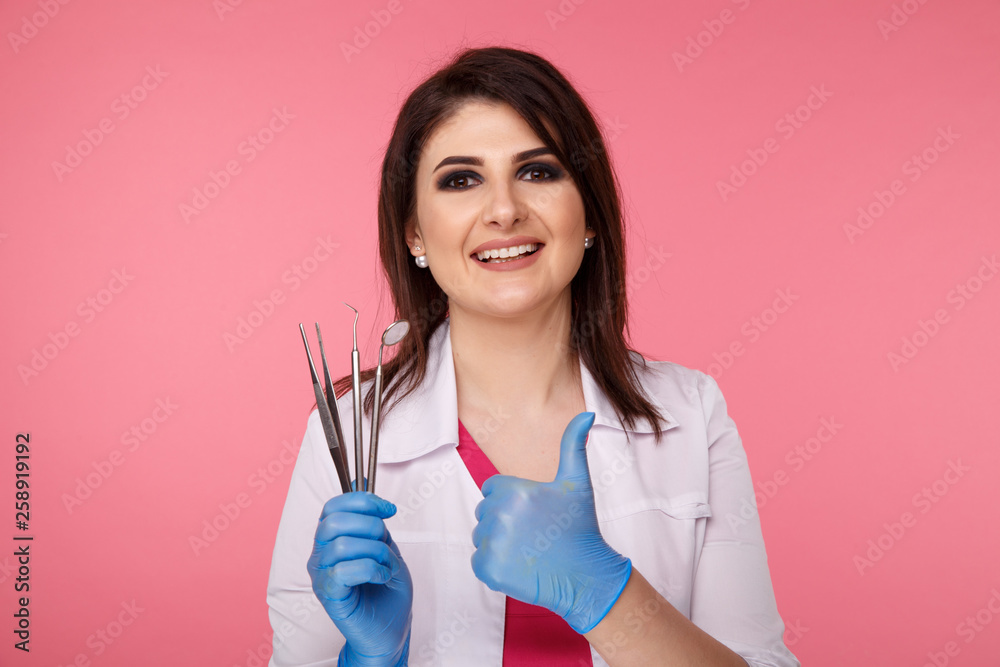 Woman dentist posing with dental tools isolated over the pink background Woman dentist posing with dental tools isolated over the pink background