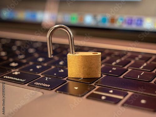 Padlock unlocked on laptop keyboard symbolising website / online / cyber security. 