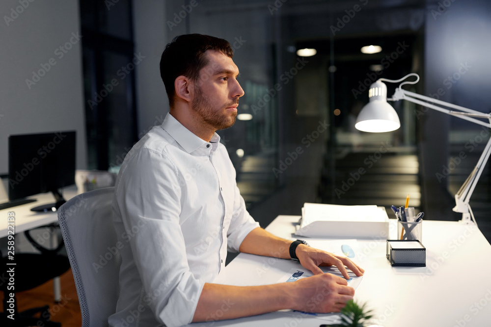 Fototapeta premium business, deadline and people concept - businessman sitting at table at night office