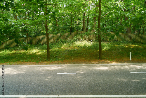 Gerade leere Straße vor Zaun auf Hügel photo