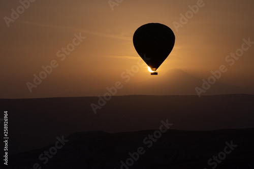 Hot air balloons flying over spectacular Cappadocia on sunset.