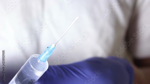 Doctor's hands fill the syringe with vaccine, preparing for the injection of the injection to the patient. Hands close up. photo