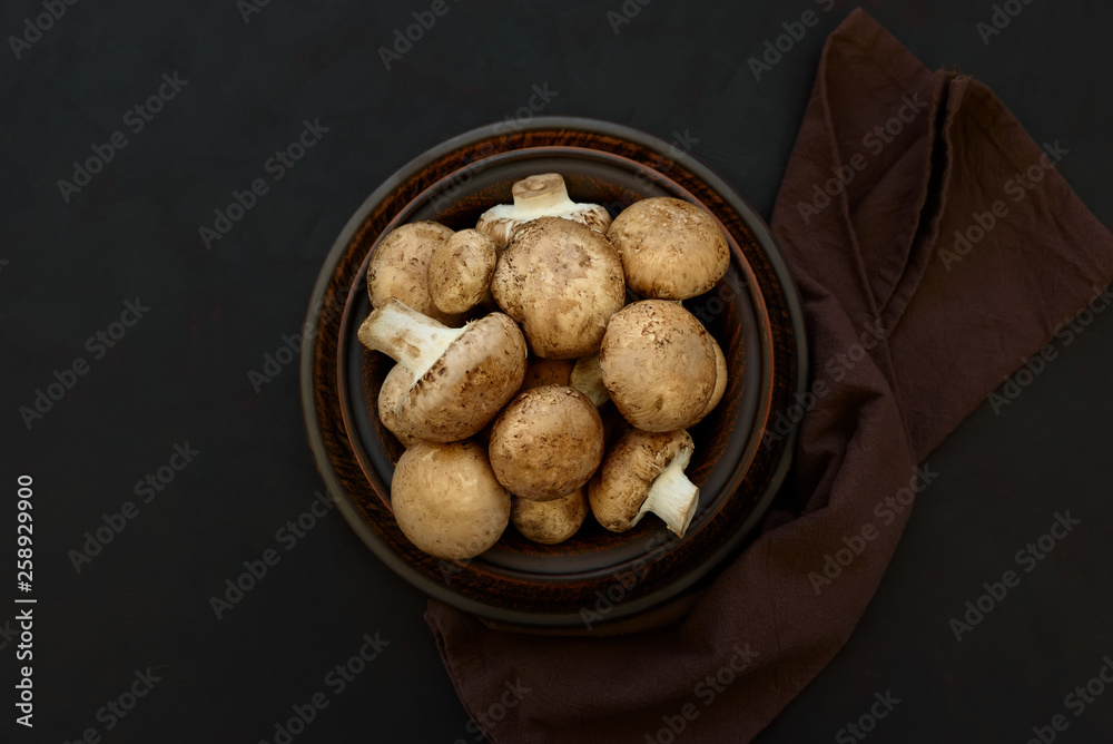 Brown champinon mushrooms (agaricus) in bowl on rustic wooden background. Healthy eating or vegetarian concept. Copy space. Top view Brown champinon mushrooms (agaricus) in bowl on rustic wooden background. Healthy eating or vegetarian concept. Copy space. Top view