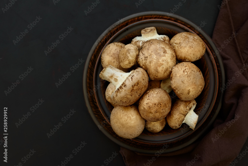 Brown champinon mushrooms (agaricus) in bowl on rustic wooden background. Healthy eating or vegetarian concept. Copy space. Top view Brown champinon mushrooms (agaricus) in bowl on rustic wooden background. Healthy eating or vegetarian concept. Copy space. Top view
