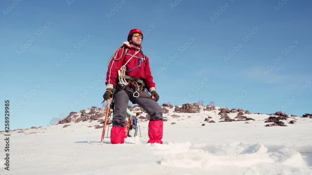bottom view of the bearded climber, who looks into the distance and turns to the side. he is dressed in warm clothes, he has an ice pick in his hand. bottom view of the bearded climber, who looks into the distance and turns to the side. he is dressed in warm clothes, he has an ice pick in his hand.