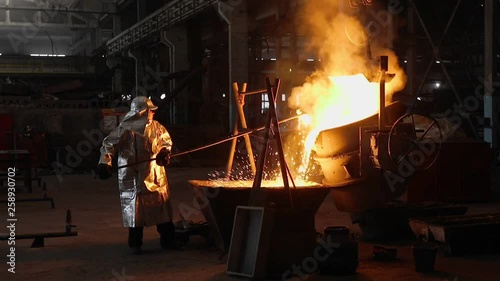 Man working with liquid metal in factory. Metal factory
