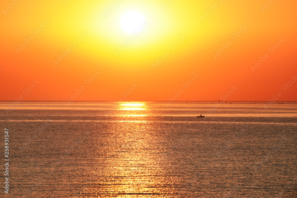 The sun rises above the surface of the sea and a boat on the water. The sun rises above the surface of the sea and a boat on the water.