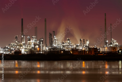 Reflection of refineries and its chimney during the on fire sunset golden hour moment at Rotterdam, Netherlands