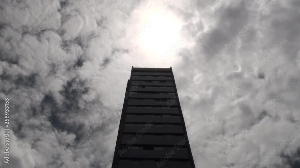 Standing a high rise on a cloudy ,sunny day Standing a high rise on a cloudy ,sunny day