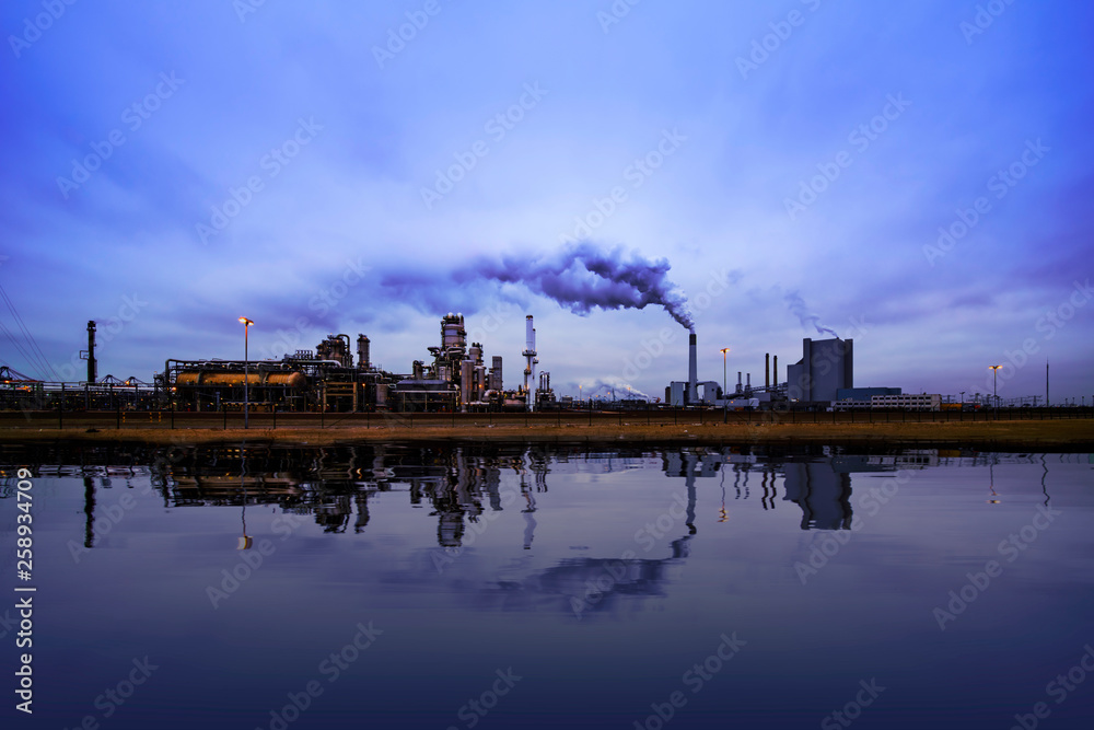 Fototapeta premium Reflection of refineries and its chimney during the on blue sunset hour moment at Rotterdam, Netherlands