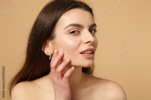 Schilderij op canvas Close up brunette half naked woman 20s with perfect skin, nude make up isolated on beige pastel wall background, studio portrait