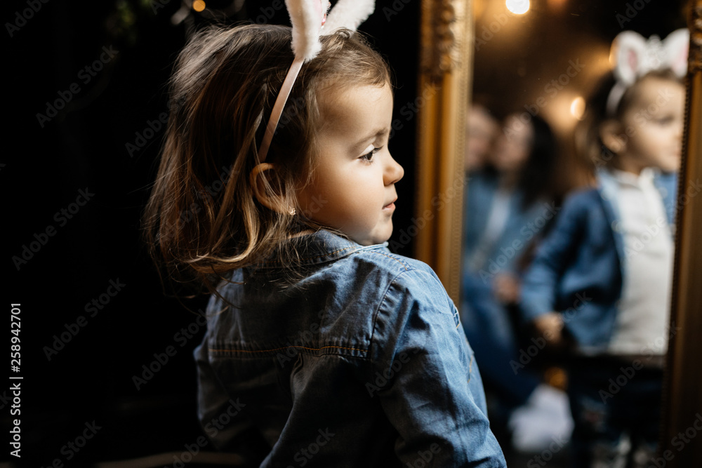 Little girl with bunny ears looks sideways