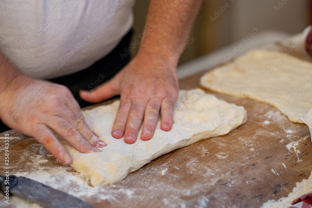 Pizza maker is kneading pizza dough