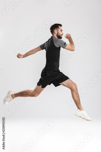 Handsome young sports fitness man posing isolate over white wall background jumping.
