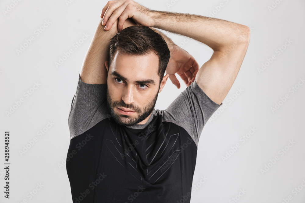 Young sports fitness man posing isolate over white wall background make stretching exercises.