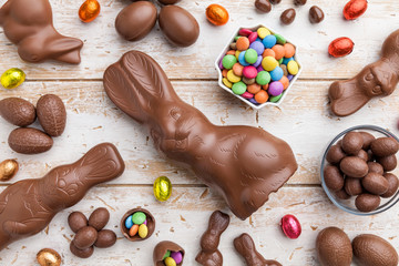 Chocolate Easter bunny, eggs and sweets on rustic background