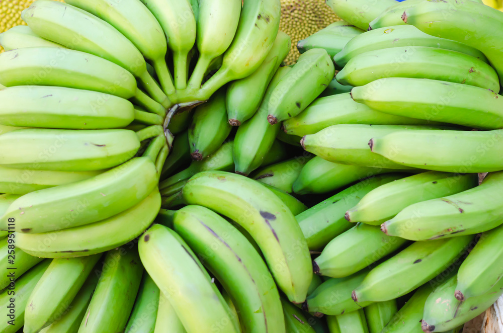image of green bananas stacked for sale