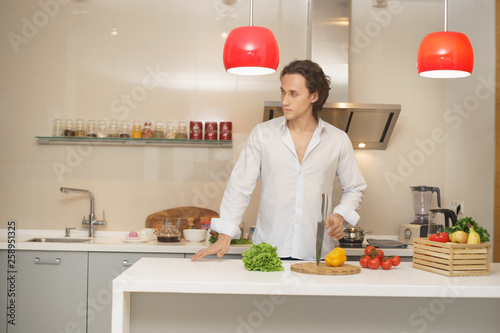 Casual man preparing salad at home in kitchen