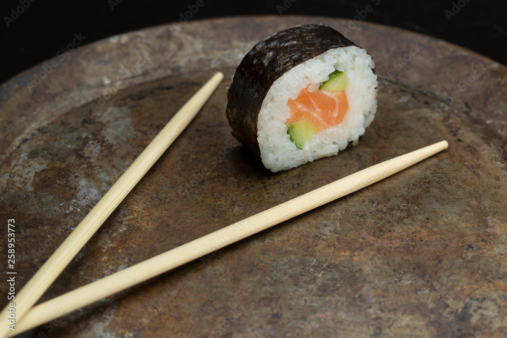 Sushi rolls on a dark metal plate, with chopsticks Sushi rolls on a dark metal plate, with chopsticks