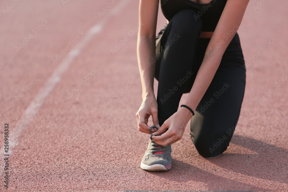 Asia woman runner tying her shoes preparing for a run on lane.