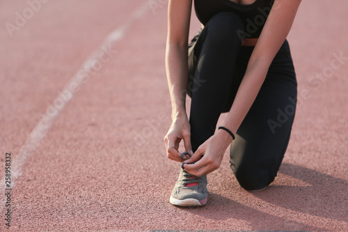 Asia woman runner tying her shoes preparing for a run on lane.