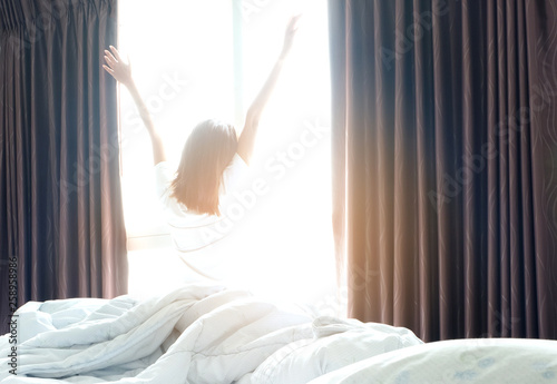 Morning of a new day, alarm clock wake up man sitting in the room. A man stretch the muscles at window. Health and care concepts