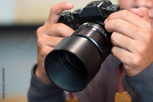 Photographer holding mirrorless camera for check his photo in selective focus.