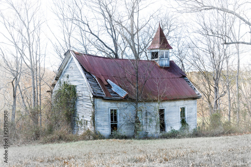 An old country church with a red metal roof, stands in disrepair on a back road in rural Tennessee.