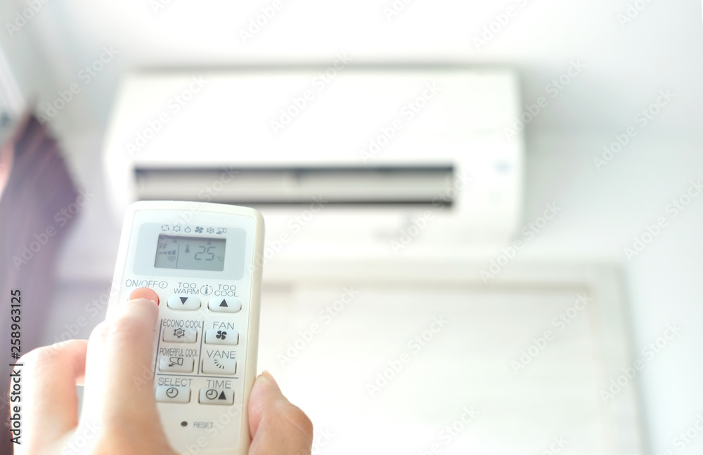 Man's hand using remote control open The air conditioner is cooled to 25 degrees Celsius in his bedroom. Health concepts and energy savings Man's hand using remote control open The air conditioner is cooled to 25 degrees Celsius in his bedroom. Health concepts and energy savings