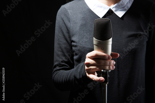 Female singer on the stage holding a microphone on a dark background photo