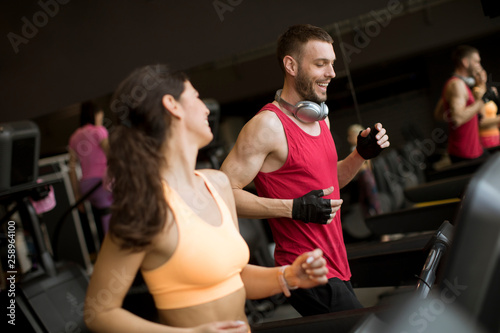 Young couple running on treadmills in modern gym