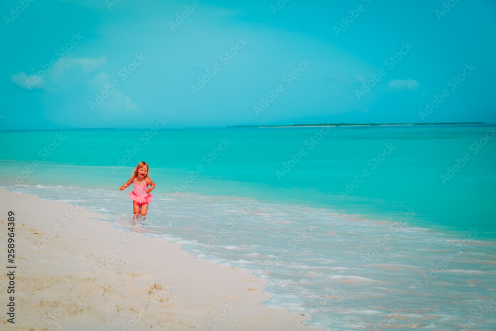 happy cute little girl play with waves on the beach