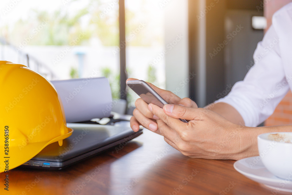 Fototapeta premium Selective focus of Casual young business engineer man hand using mobile smart phone with coffee blurred background