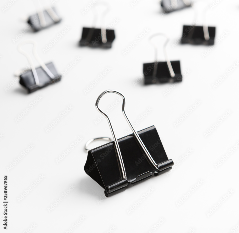 One binder clip standing out of others on white One binder clip standing out of others on white