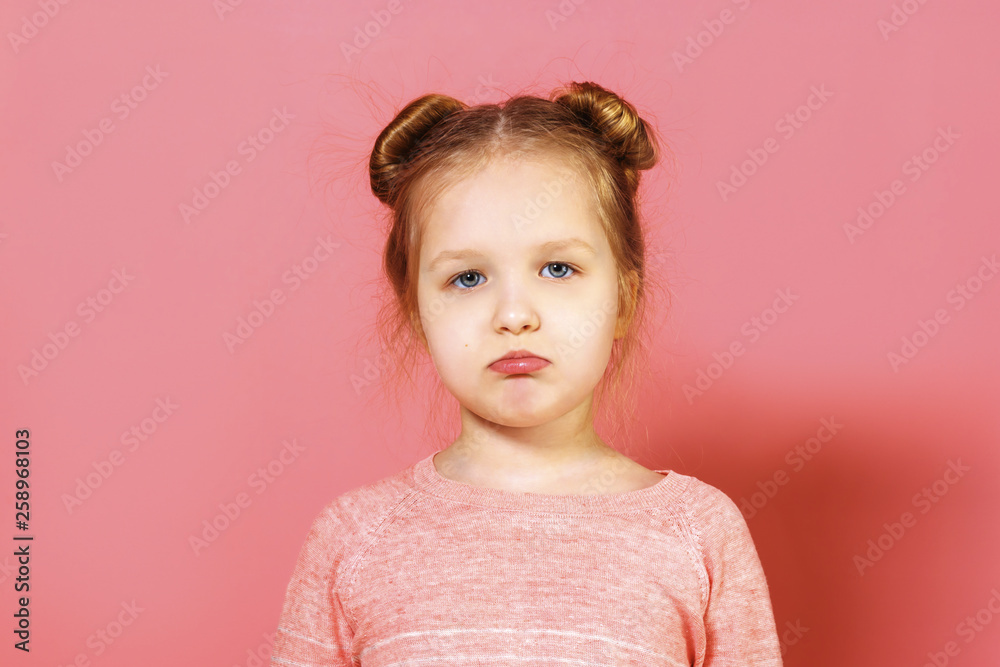Closeup portrait of upset little girl with wisps of hair over pink background. The child pouted his lips. Closeup portrait of upset little girl with wisps of hair over pink background. The child pouted his lips.