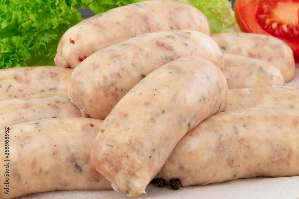 Fresh raw sausage with lettuce and tomato on the wooden background Fresh raw sausage with lettuce and tomato on the wooden background